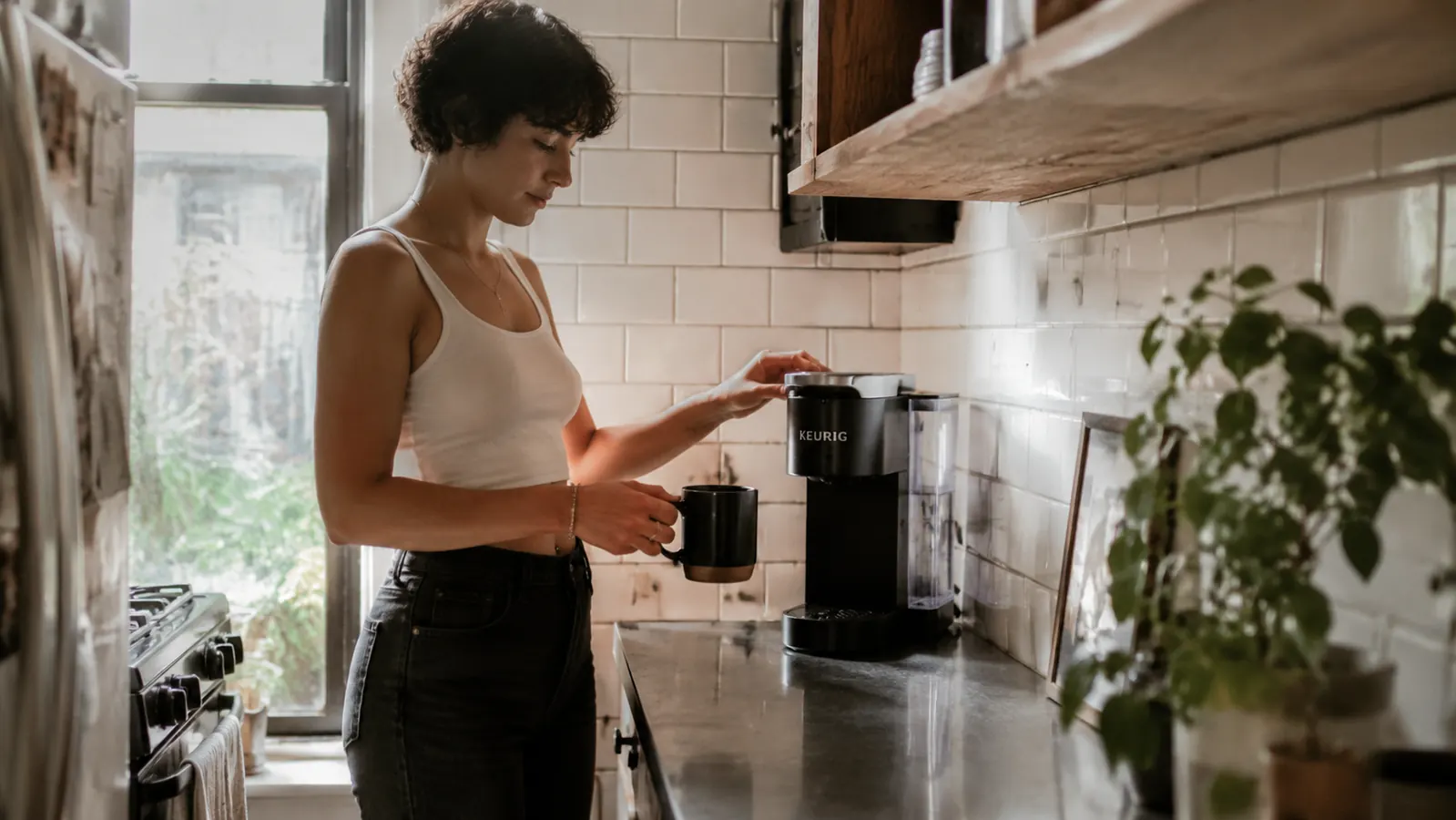 Keurig K-Mini coffee maker sitting on a narrow kitchen counter beside a subway-tile backsplash in a compact apartment kitchen